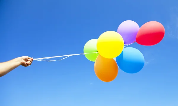Χέρι που κρατά τα πολύχρωμα μπαλόνια — Φωτογραφία Αρχείου