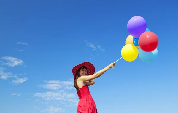 Chica morena con globos de color en el fondo del cielo azul . — Foto de Stock