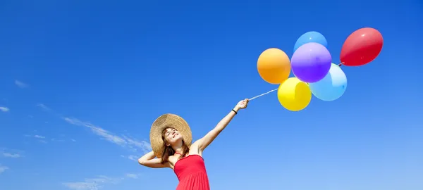 Brunette meisje met kleur ballonnen bij blauwe hemelachtergrond. — Stockfoto