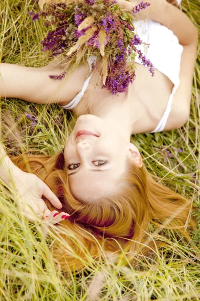Rusovláska dívka na venkovní s květinami. — Stock fotografie