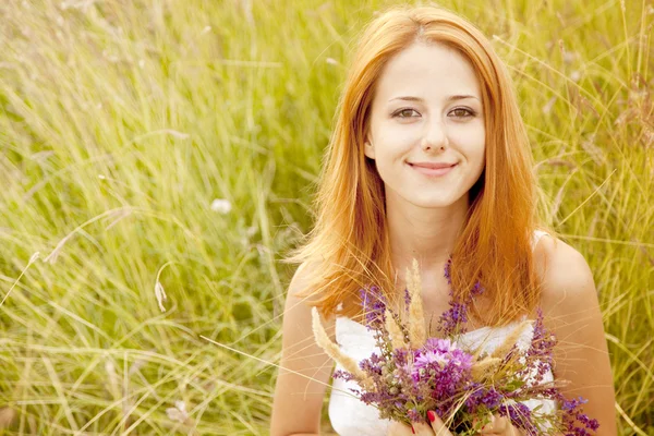 Rödhårig flicka på utomhus med blommor. — Stockfoto