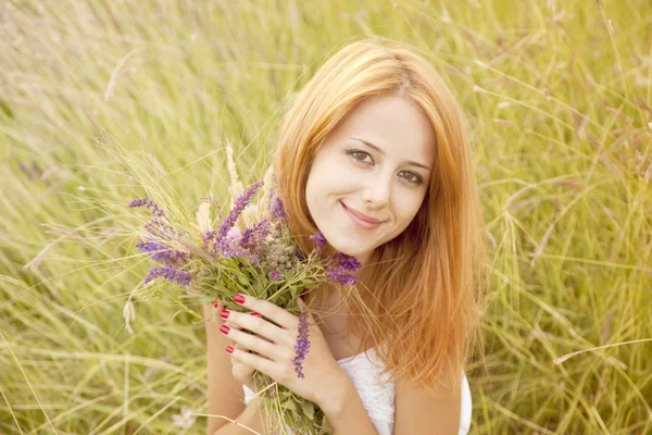 Roodharige meisje op buiten met bloemen. — Stockfoto