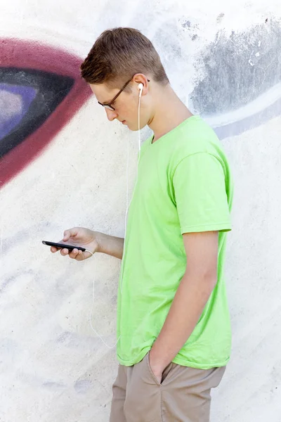 Adolescente con auricolari vicino muro graffiti — Foto Stock