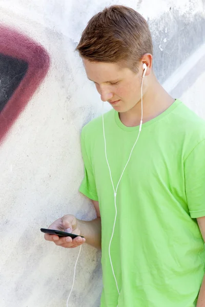 Tiener jongen met koptelefoon in de buurt van graffiti muur — Stockfoto