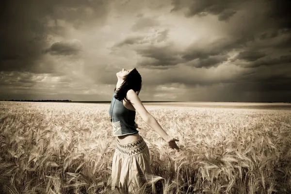 Dívka v pšeničné pole. Foto v tmavých barvách s malým šumem. — Stock fotografie
