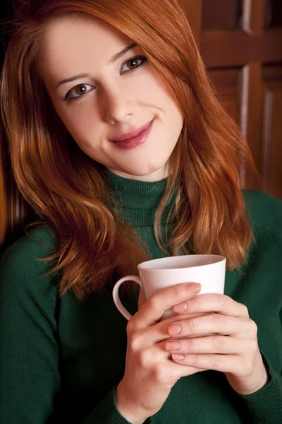 Estilo chica pelirroja beber café cerca de puertas de madera . —  Fotos de Stock