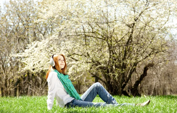Vöröshajú lány a parkban fejhallgató. — Stock Fotó
