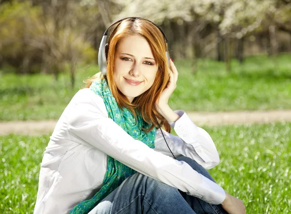 Руда дівчина з навушниками в парку . — стокове фото