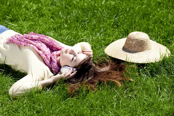 Brunette meisje met hoofdtelefoon ligt in het park. — Stockfoto
