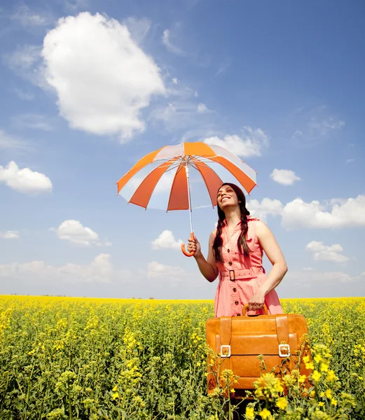 Brunette enchantress with umbrella and suitcase at spring rapese — Stock Photo, Image