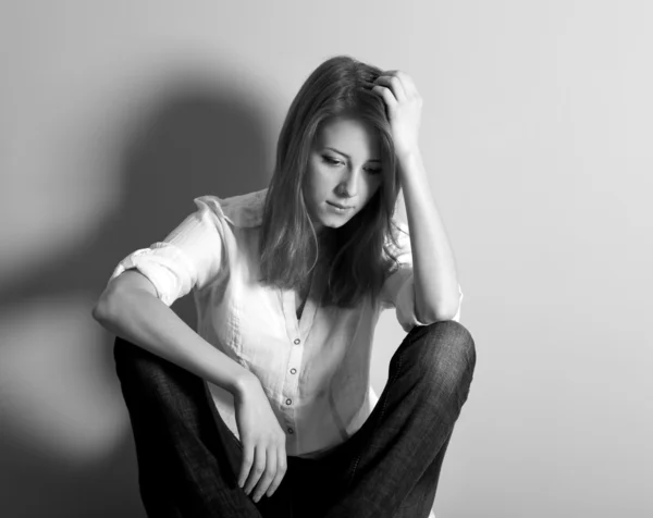 Ledsen tonåring tjej på golvet nära väggen. Foto i svart och vit stil — Stockfoto