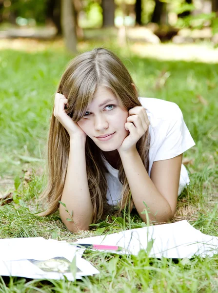 Szőke lány csinál házi feladatot a parkban. — Stock Fotó