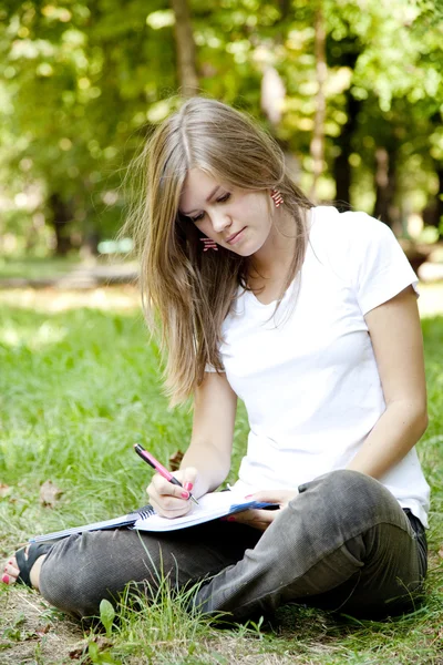 Menina loira fazendo lição de casa no parque . — Fotografia de Stock
