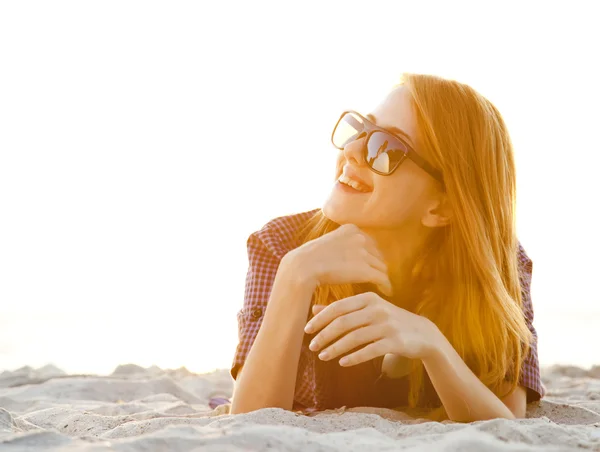Menina de cabeça vermelha com fones de ouvido na praia ao nascer do sol . — Fotografia de Stock