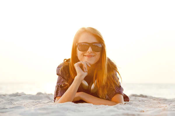 Chica pelirroja con auriculares en la playa al amanecer . —  Fotos de Stock