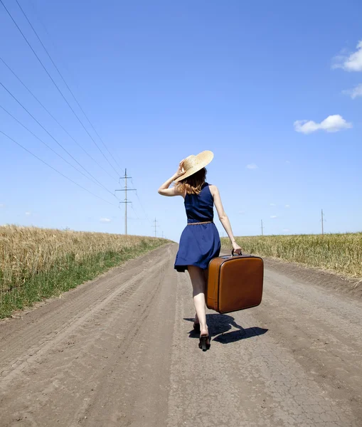 Eenzaam meisje met koffer in landweg. — Stockfoto