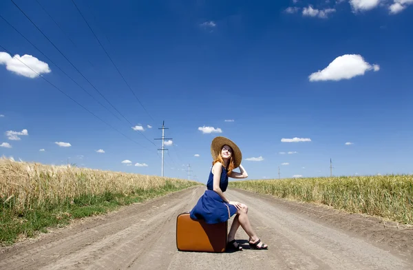 孤单的小女孩带着手提箱在乡村道路. — 图库照片