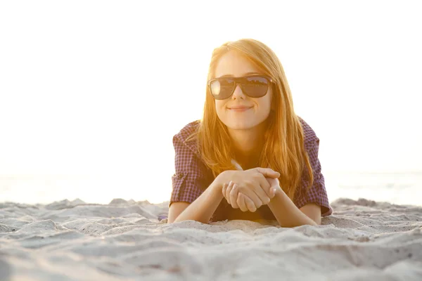 Red-head flicka med hörlurar på stranden i soluppgång. — Stockfoto
