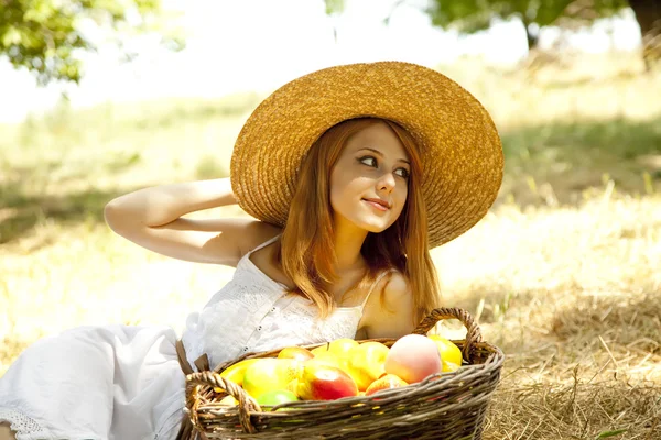 Beautiful redhead girl with fruits in basket at garden. Royalty Free Stock Images