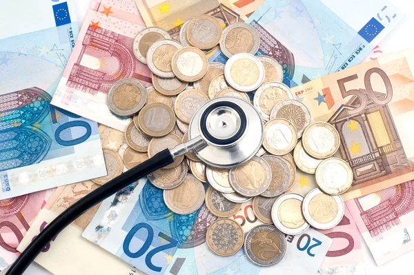 Concept van dure gezondheidszorg met munten, biljetten en stethoscoop — Stockfoto
