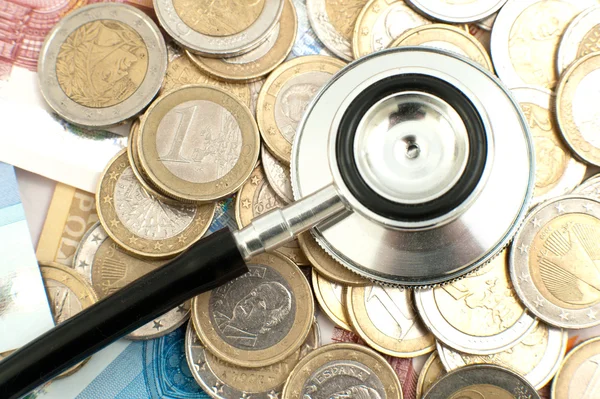 Concept van dure gezondheidszorg met munten, biljetten en stethoscoop — Stockfoto