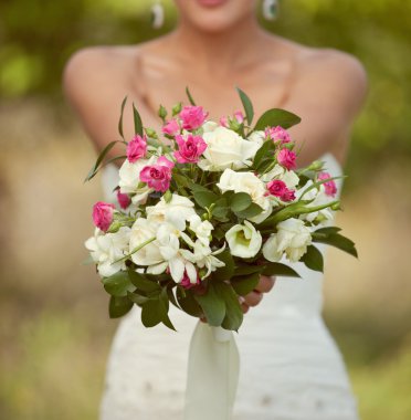 Pink and white wedding bouquet of roses in the hands of the brid clipart