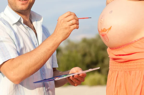 Happy husband draws on his belly pregnant wife — Stock Photo, Image