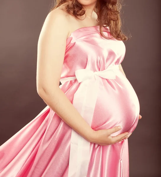 Mulher grávida em um vestido rosa com um arco — Fotografia de Stock