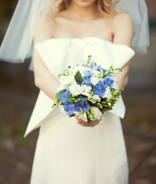 Ramo nupcial de flores blancas y azules en las manos del bri — Foto de Stock