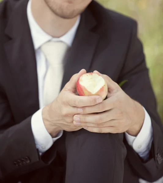 Groom in a wedding jacket with an apple in his hand — Stock Photo, Image