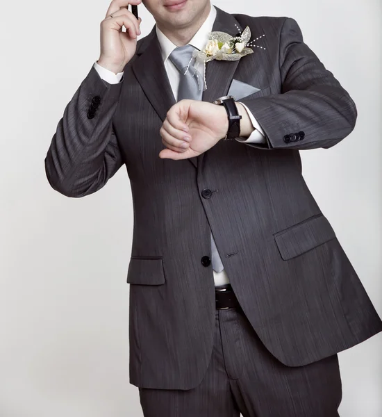 Groom in a wedding jacket looks at his watch and calls on his mo — Stock Photo, Image