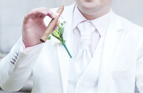 Lo sposo in una giacca da sposa bianca con boutonniere e un sigaro — Foto Stock