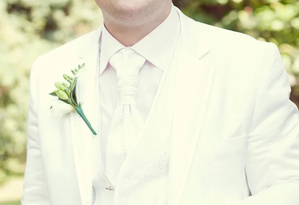 Ο γαμπρός σε ένα άσπρο γαμήλιο σακάκι με μπουτονιέρα — Φωτογραφία Αρχείου