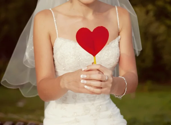 Bride with a red heart in hands — Stock Photo, Image