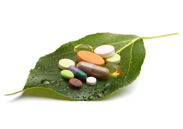 Vitamine, compresse e pillole su foglia verde — Foto Stock
