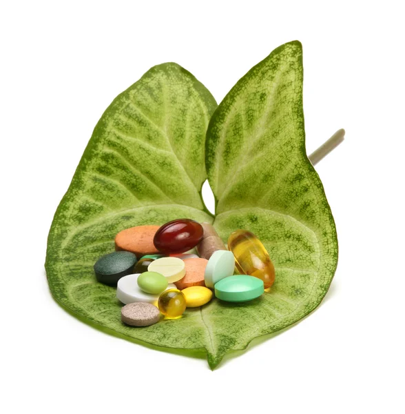 Vitaminas, tabletas y pastillas en hoja verde — Foto de Stock