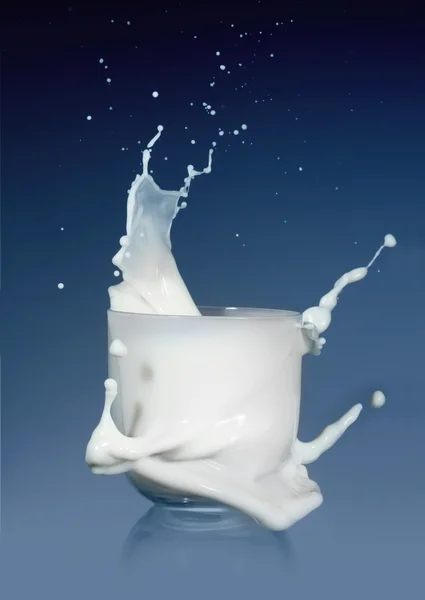 Splash mleczne szkło na niebieskim tle — Zdjęcie stockowe