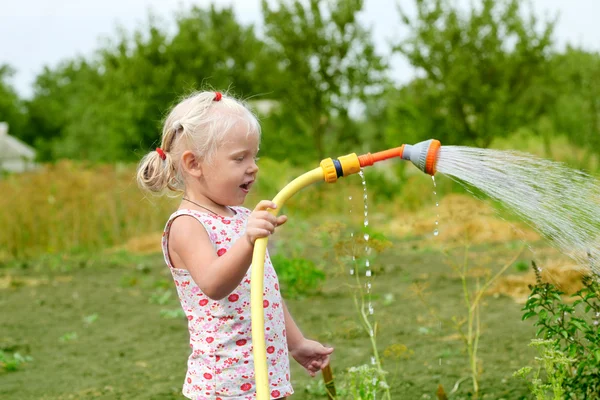 Bahçedeki çimleri sulayan küçük kız — Stok fotoğraf