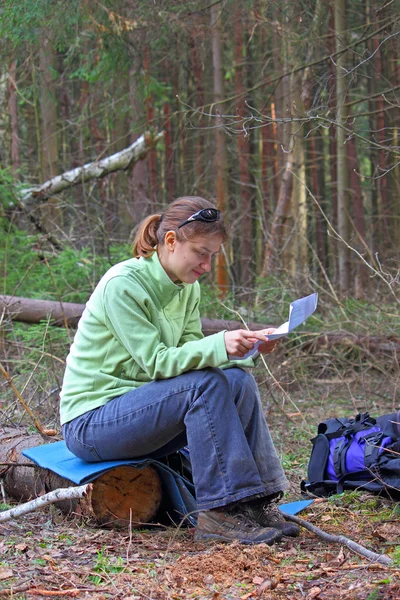 Menina-viajante na floresta lendo um mapa — Fotografia de Stock