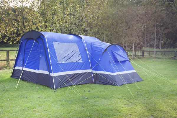 Blå tält i skuggat område nära skogen — Stockfoto