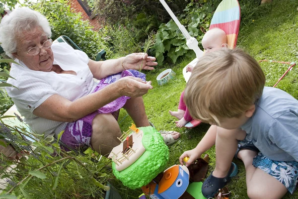 Gran és gran játszó gyermekek kívül a kertben — Stock Fotó