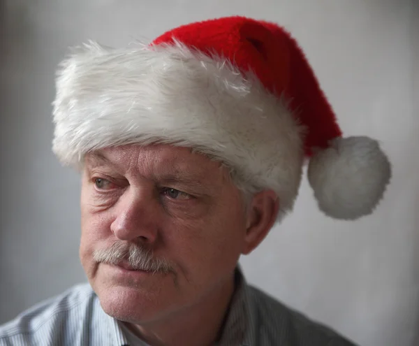 Annoyed senior with a Santa hat — Stock Photo, Image