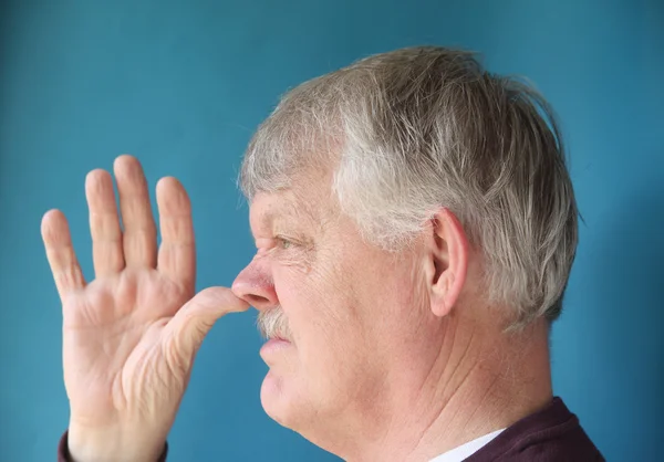 Hombre mayor pulgares su nariz — Foto de Stock
