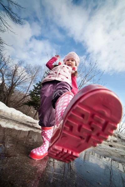 Um meninas botas rosa salpicando em uma poça enlameada — Fotografia de Stock