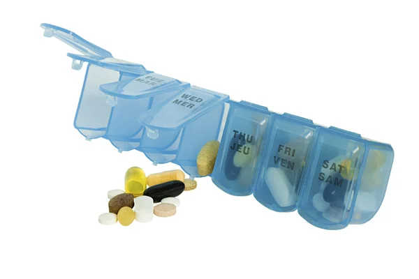 Pastillas de prescripción, vitaminas y medicamentos en una caja de pastillas azul días de la semana aislados en blanco —  Fotos de Stock