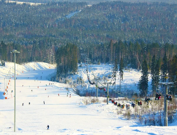 stock image Ski chair-lift with skiers and snowborders and high mountain slope with riding