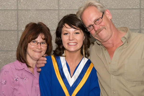 Junge Frau im Abschlussdress mit Familie Stockfoto