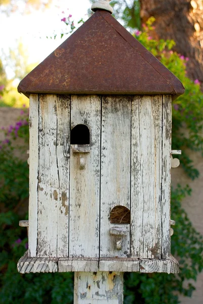 Casa de pássaro branco com telhado enferrujado — Fotografia de Stock