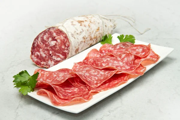 Salami in Scheiben geschnitten auf Marmortisch — Stockfoto