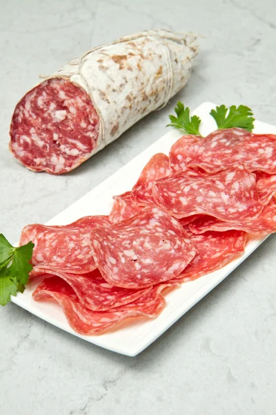 Salami in Scheiben geschnitten auf Marmortisch — Stockfoto